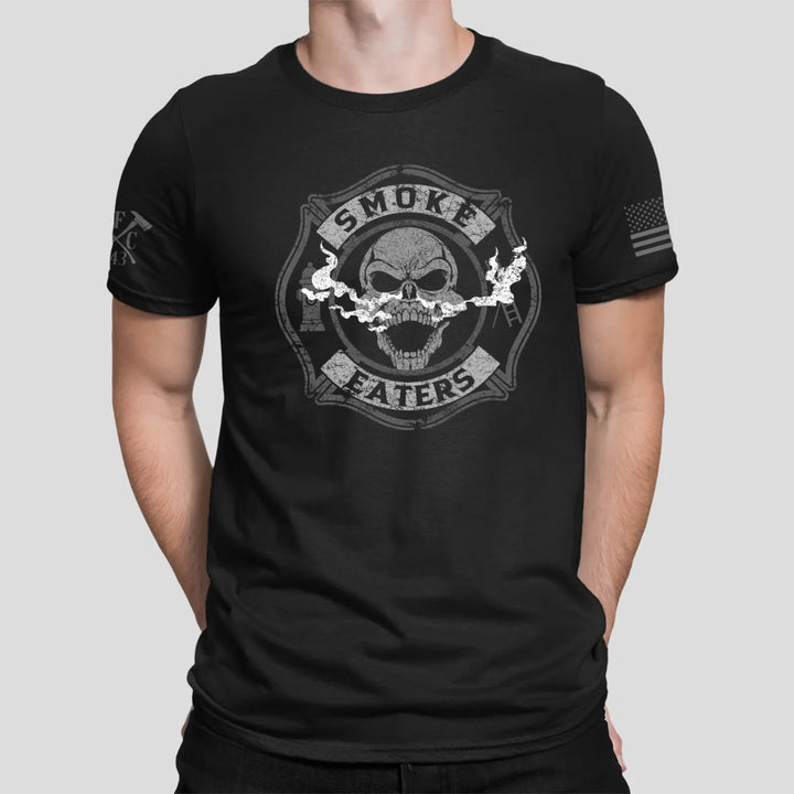 a man wearing a black firefighter t-shirt in black color featuring full-front design of a skull inhaling smoke, with a distressed grey and off-white look.