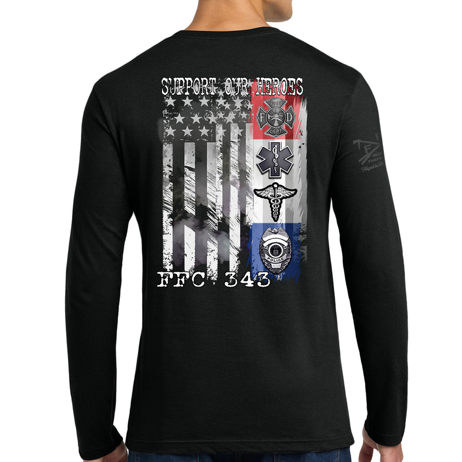 A man wearing a black long-sleeve t-shirt, viewed from the back. The shirt features a large graphic print on the back with a distressed American flag, military-style emblems, and the text 'SUPPORT OUR HEROES' and 'FFC 343'. #color_black