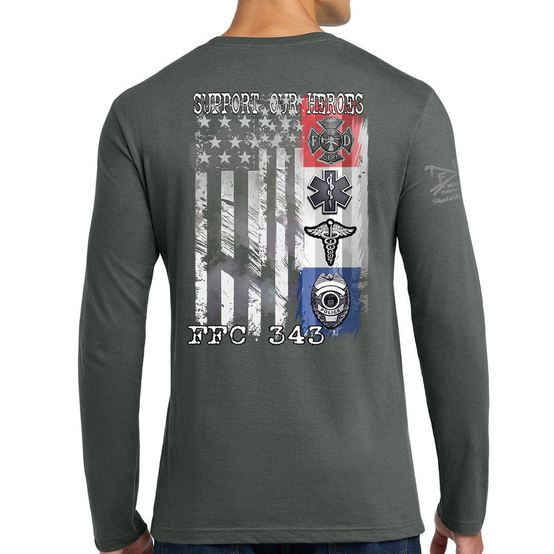 A man wearing a dark gray long-sleeve t-shirt, viewed from the back. The shirt features a large graphic print on the back with a distressed American flag, military-style badges, and the text 'SUPPORT OUR HEROES' and 'FFC 343'. #color_charcoal
