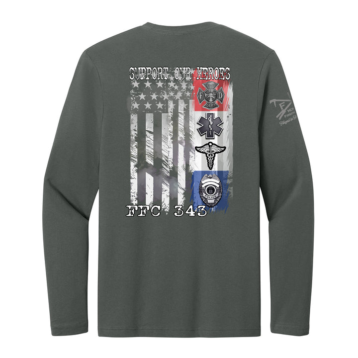A dark gray long-sleeve t-shirt shown from the back, featuring a large graphic print of a distressed American flag with military and emergency services symbols, including a firefighter helmet, EMT star, and ambulance cross. The text 'SUPPORT OUR HEROES' is printed above the flag, and 'FBC 343' is printed below. #color_charcoal