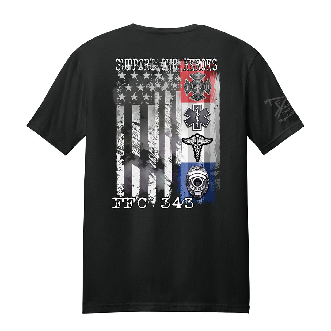 A black short-sleeve t-shirt shown from the back, featuring a large distressed graphic of the American flag with military and emergency services symbols, including a fire department helmet, EMT star, ambulance cross, and police badge. The text 'SUPPORT OUR HEROES' is printed above the flag, and 'FFC 343' is printed below.
