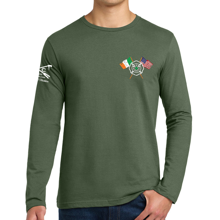 A man wearing a dark green long-sleeve t-shirt with a crossed flags graphic on the left chest (Irish flag, Ireland football club crest, and US flag) and a white graphic on the right sleeve. #color_military-green