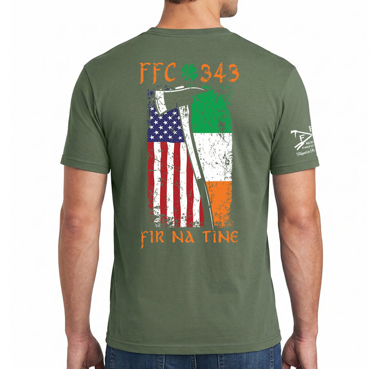 A man wearing an olive green t-shirt, viewed from the back. The shirt features a distressed graphic of the Irish flag and the American flag with an axe, along with the text 'FFC 343' and 'FIR NA TINe'. #color_military-green