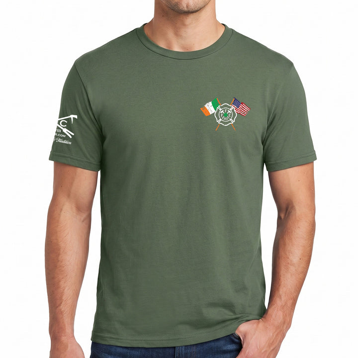 An olive green crewneck t-shirt worn by a model, featuring a small graphic on the left chest with crossed firefighter helmets and Irish and American flags, and a white graphic on the right sleeve. #color_military-green