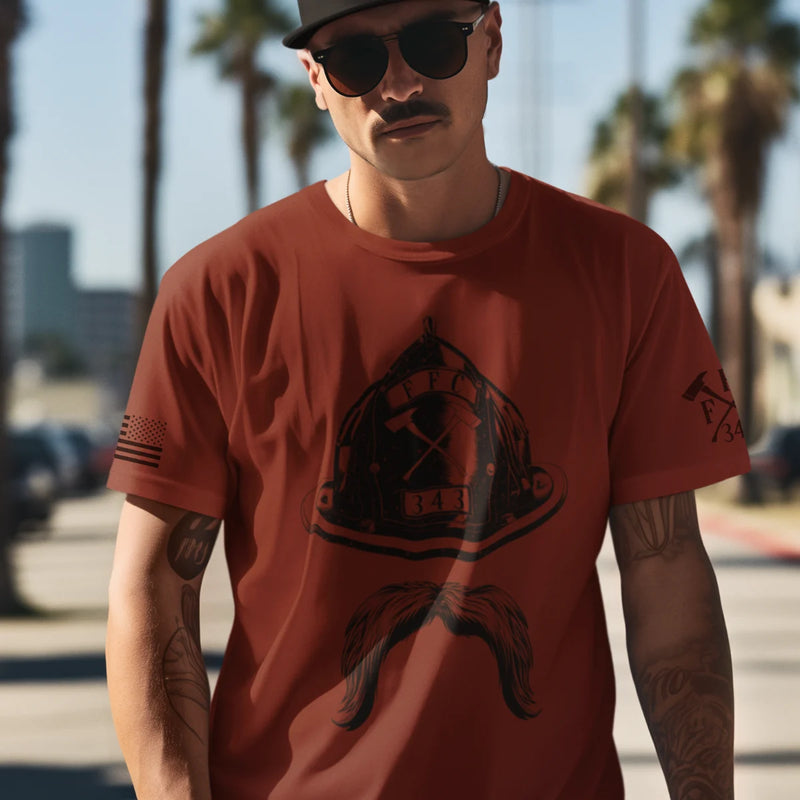 A man wearing a firefighter T-shirt in red with a full front design featuring a firefighter helmet and mustache.