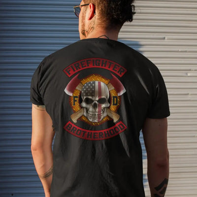 A man wearing a black firefighter T-shirt with a full back design featuring a skull design with an American flag and crossed axes