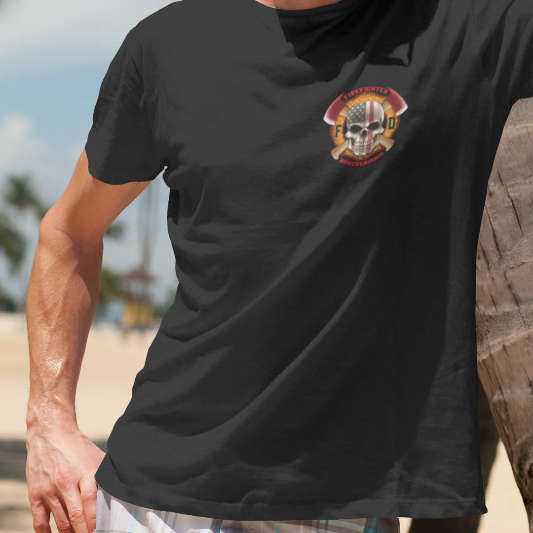 A man wearing a black firefighter T-shirt with a left chest print featuring a skull design with an American flag and crossed axes