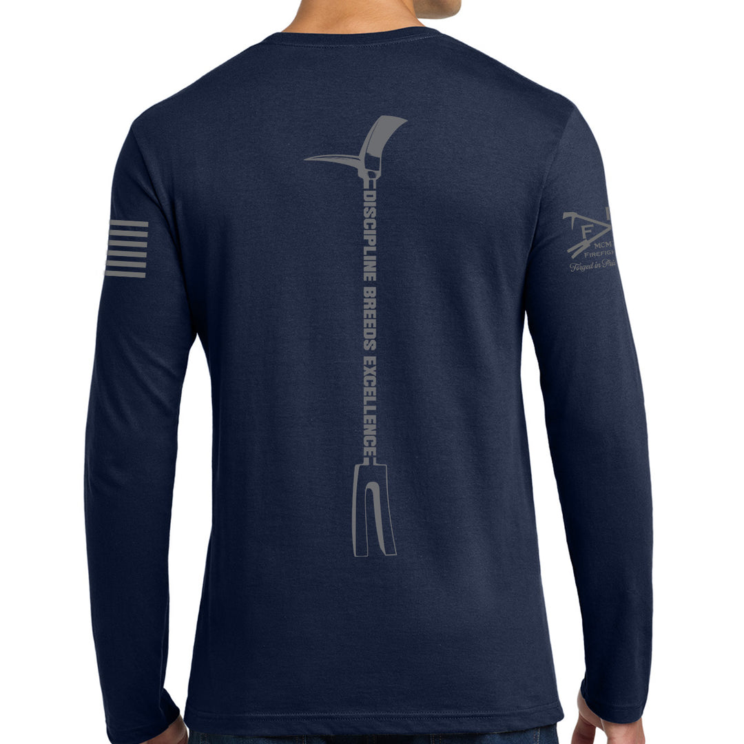 A man wearing a navy blue long-sleeve t-shirt, viewed from the back. The shirt features a large gray graphic of a pickaxe with the text 'DISCIPLINE BREEDS EXCELLENCE' printed vertically down the center back, and smaller gray graphics on both sleeves. #color_navy
