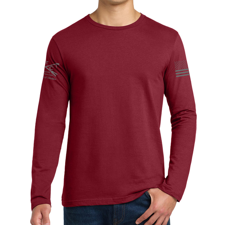 A man wearing a heathered burgundy long-sleeve t-shirt with a dark gray graphic on the right sleeve and a distressed American flag graphic on the left sleeve, paired with blue jeans against a white background. #color_cardinal-red
