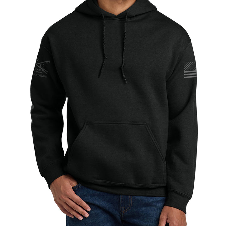 A man wearing a black pullover hoodie with a kangaroo pocket and subtle gray sleeve graphics, paired with blue jeans, against a plain white background. #color_black