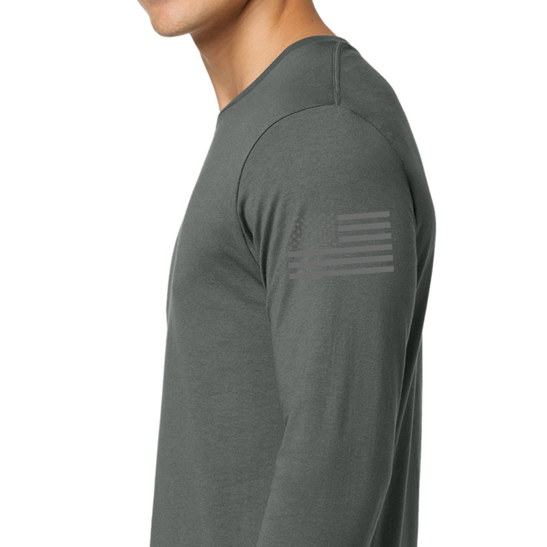 A man wearing a dark gray long-sleeve athletic shirt, shown in a side profile against a plain white background. A subtle, tonal American flag graphic is printed on the upper left sleeve. #color_charcoal