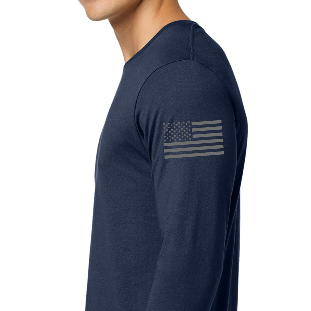 A man wearing a navy blue long-sleeve shirt, shown from the side. The shirt features a faded gray American flag graphic printed on the upper left sleeve. #color_navy