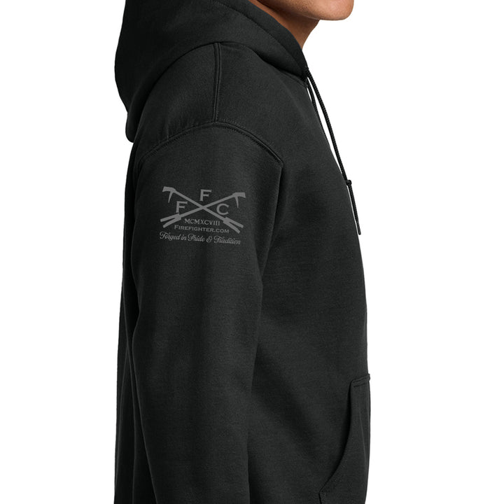 A close-up side view of a person wearing a black pullover hoodie with a gray and white FfC emblem printed on the upper left sleeve, set against a plain white background.  #color_black