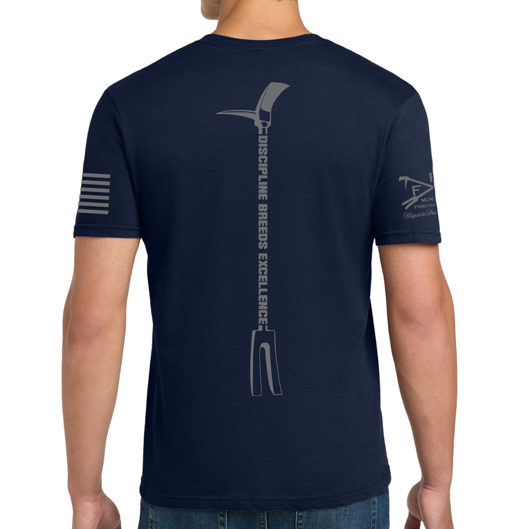 A man wearing a navy blue t-shirt, viewed from the back. The shirt features a large gray graphic of a pitchfork with the text 'DISCIPINE BREeDs EXCELLENCE' printed vertically down the center. #color_navy