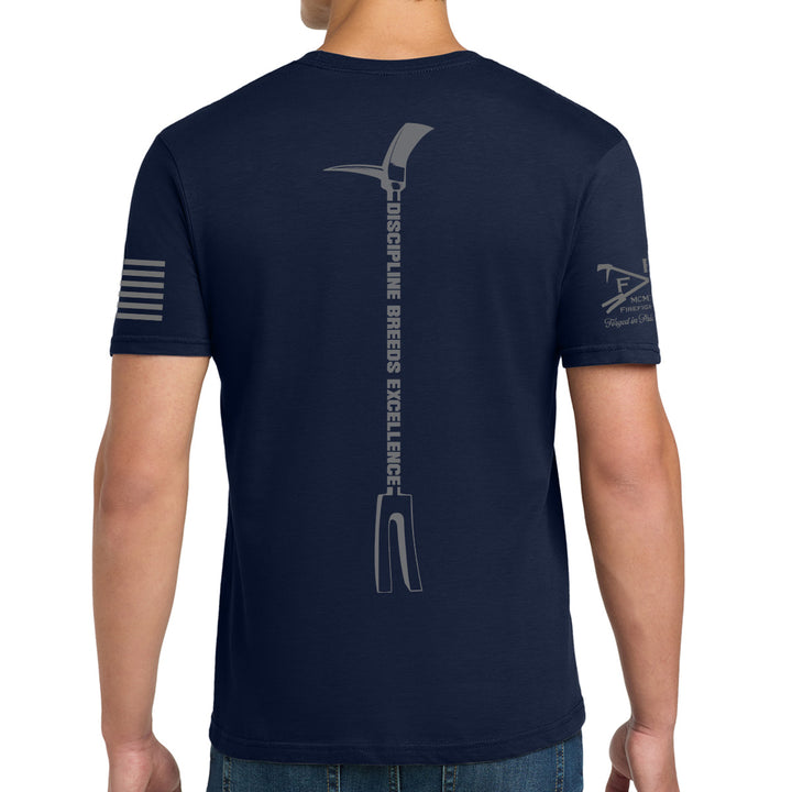 A man wearing a navy blue t-shirt, viewed from the back. The shirt features a large gray graphic of a pitchfork with the text 'DISCIPINE BREeDs EXCELLENCE' printed vertically down the center. #color_navy