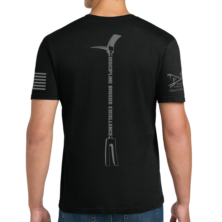 A man wearing a black short-sleeve t-shirt, viewed from the back. The shirt features a large gray graphic of a pitchfork with the words 'DISCIPLINE BREEDS EXCELLENCE' printed vertically down the center back. #color_black