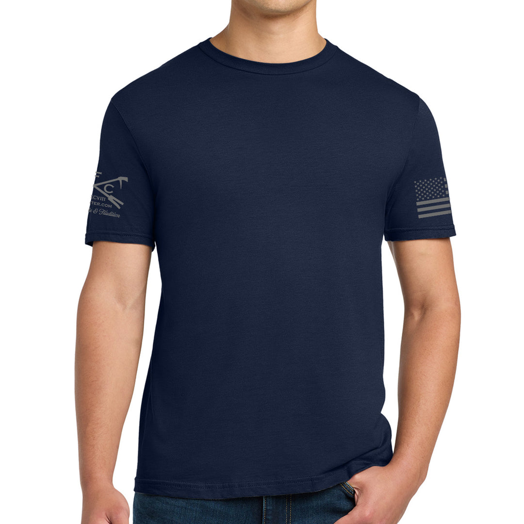 A man wearing a navy blue crewneck t-shirt with a distressed gray US Navy emblem on the left sleeve and a distressed American flag on the right sleeve, shown against a plain white background. #color_navy