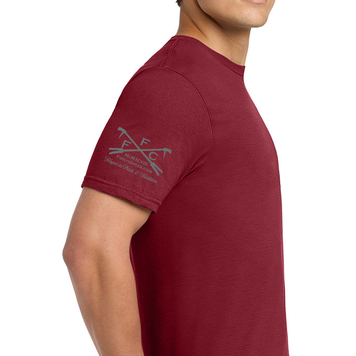 A man wearing a maroon short-sleeve t-shirt, shown from a side profile against a plain white background. The left sleeve features a gray graphic logo with crossed axes and the letters 'FFC' with text below.  #color_cardinal-red