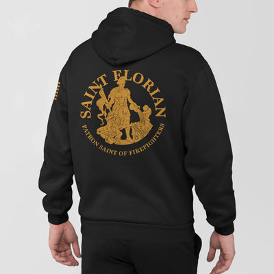 A man wearing a black firefighter hoodies shirt with a full back design featuring the Saint Florian Patron Saint of Firefighters