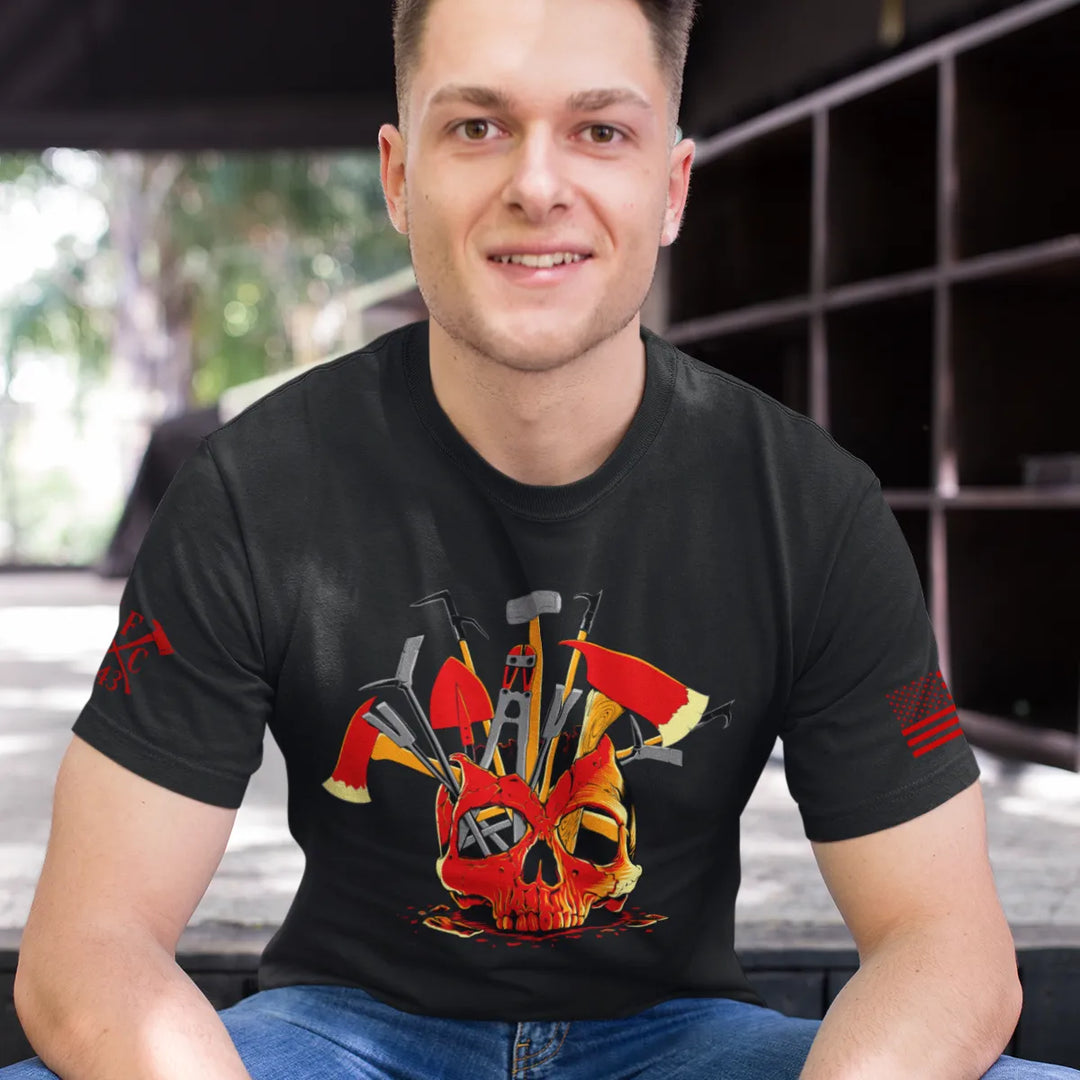 A man wearing a black firefighter T-shirt showing the full-front design of a skull filled with firefighter tools