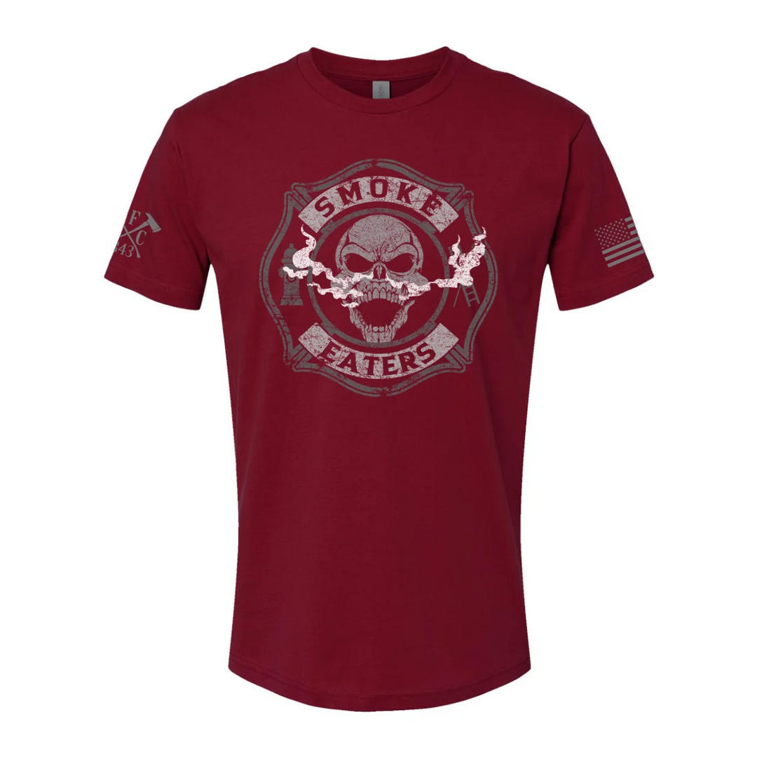 Front view of firefighter T-Shirt in cardinal red color featuring a full-front design print of a skull inhaling smoke, with a distressed grey and off-white look. 