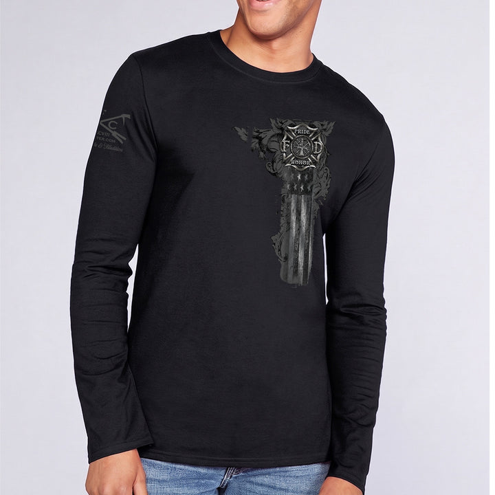 A man wearing a black long-sleeve t-shirt with a distressed, dark gray American flag graphic on the front and a logo on the left sleeve, paired with blue jeans against a light gray background.  #color_black
