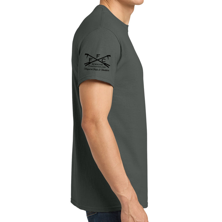A man wearing a dark gray crewneck t-shirt, shown from a side profile view against a plain white background. The shirt features a black printed graphic on the left sleeve with crossed tools and the text 'FFC' #color_charcoal